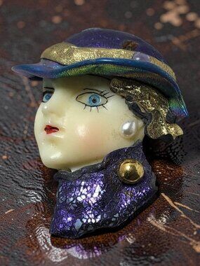 Vintage Art Deco-style brooch stylized woman's face with a purple hat, shimmerin